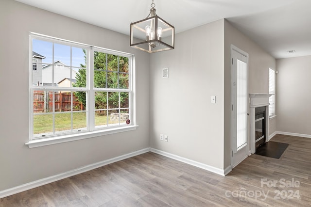 unfurnished dining area with a notable chandelier, wood-type flooring, and plenty of natural light