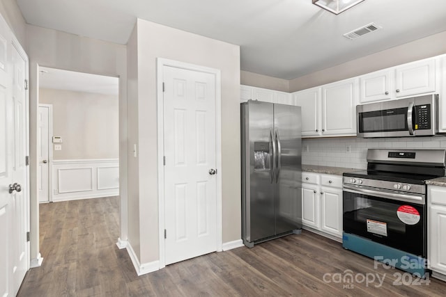 kitchen featuring light stone counters, white cabinets, dark wood-type flooring, stainless steel appliances, and decorative backsplash