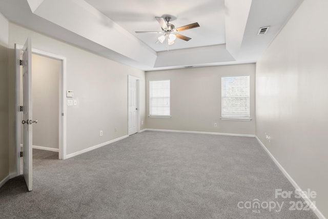 spare room featuring ceiling fan, a raised ceiling, and carpet flooring