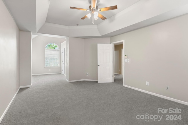 spare room featuring carpet, ceiling fan, and a raised ceiling