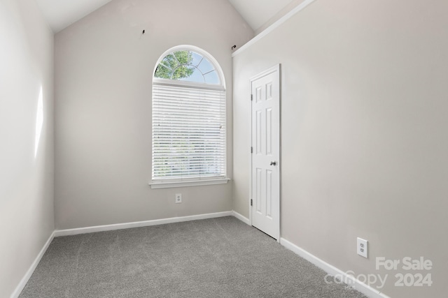 carpeted empty room with lofted ceiling