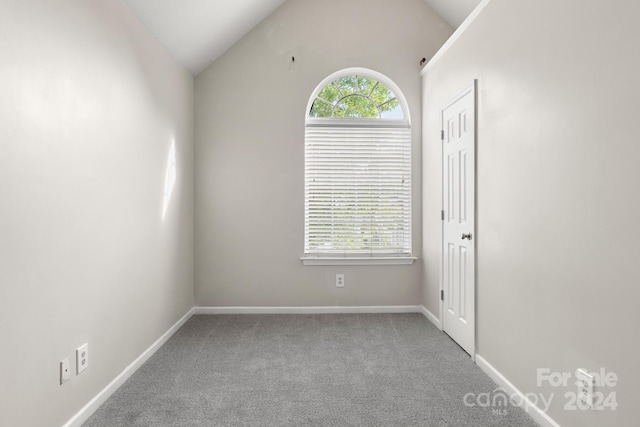 carpeted spare room with vaulted ceiling