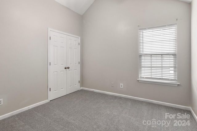 spare room featuring carpet floors and lofted ceiling