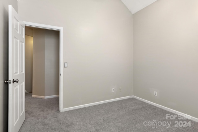 spare room featuring light carpet and lofted ceiling