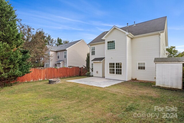 back of house with a shed, a fire pit, a lawn, and a patio