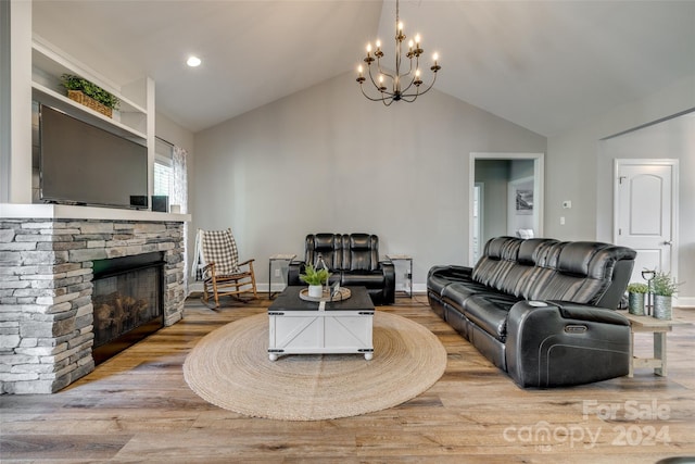 living room with a fireplace, vaulted ceiling, an inviting chandelier, and light hardwood / wood-style floors