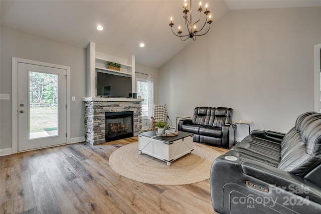 living room featuring light hardwood / wood-style flooring, vaulted ceiling, an inviting chandelier, and a fireplace