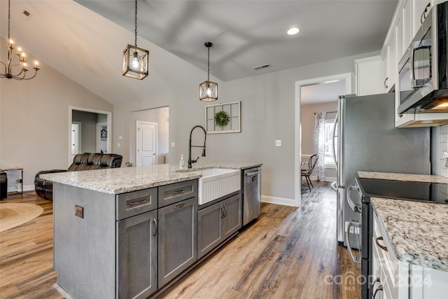 kitchen featuring stainless steel appliances, hardwood / wood-style floors, decorative light fixtures, and white cabinetry