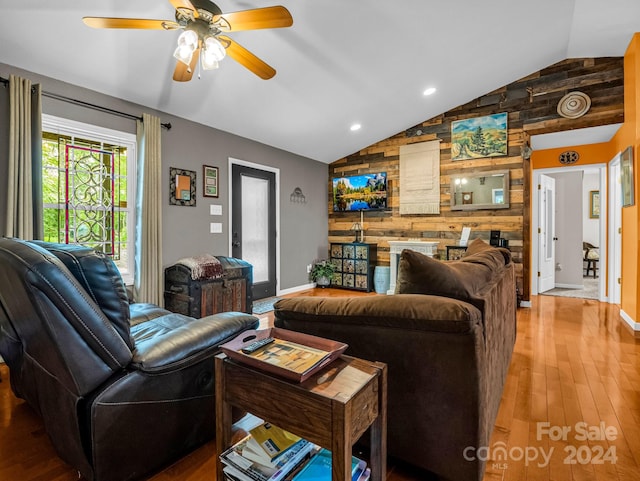 living room with vaulted ceiling, wood-type flooring, wood walls, and ceiling fan