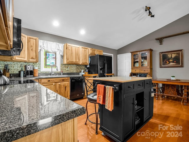 kitchen featuring a kitchen island, a breakfast bar area, vaulted ceiling, black appliances, and sink