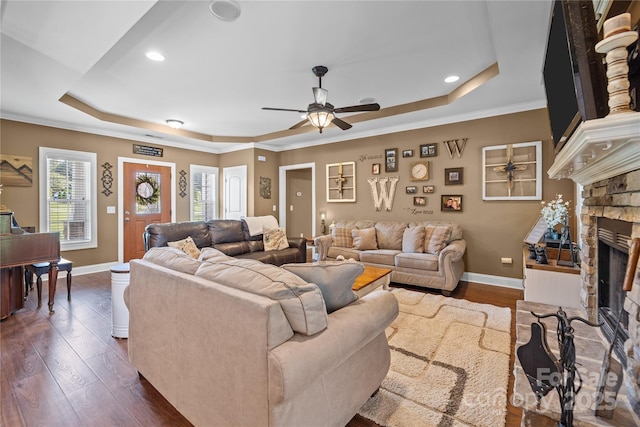 living room with crown molding, dark hardwood / wood-style floors, a fireplace, and a raised ceiling