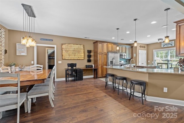 kitchen featuring hanging light fixtures, light stone countertops, dark hardwood / wood-style floors, and appliances with stainless steel finishes