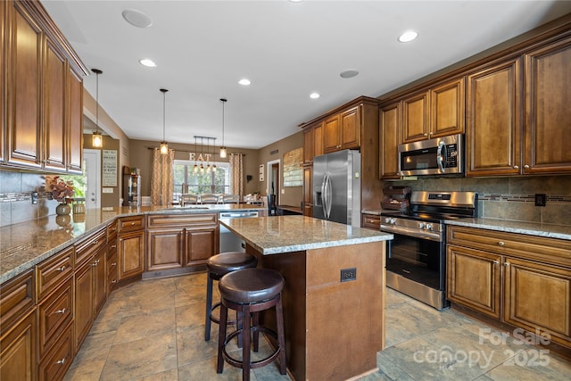 kitchen featuring hanging light fixtures, appliances with stainless steel finishes, a center island, and a kitchen bar