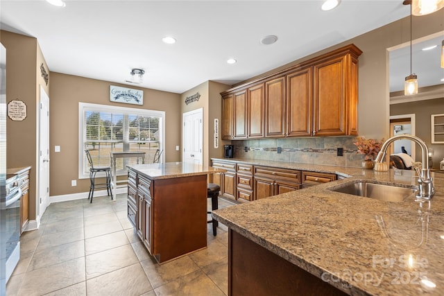 kitchen with sink, light stone countertops, a kitchen island, white range with gas cooktop, and decorative light fixtures