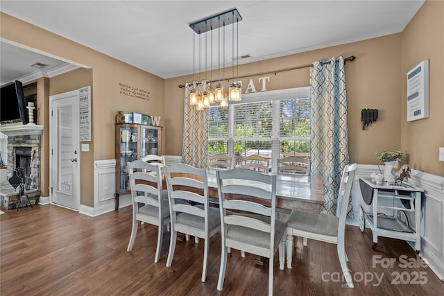 dining room featuring an inviting chandelier, dark hardwood / wood-style flooring, and a stone fireplace