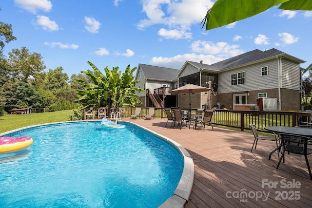 view of pool with a wooden deck and a lawn