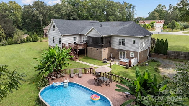 back of house with a swimming pool with hot tub, a yard, and a sunroom