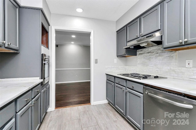 kitchen featuring a textured ceiling, light hardwood / wood-style flooring, stainless steel appliances, and gray cabinets