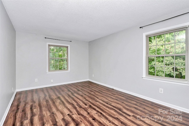 spare room with a textured ceiling and dark hardwood / wood-style floors