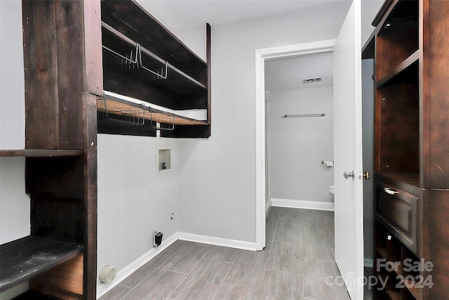 laundry room with a textured ceiling, wood-type flooring, and hookup for a washing machine