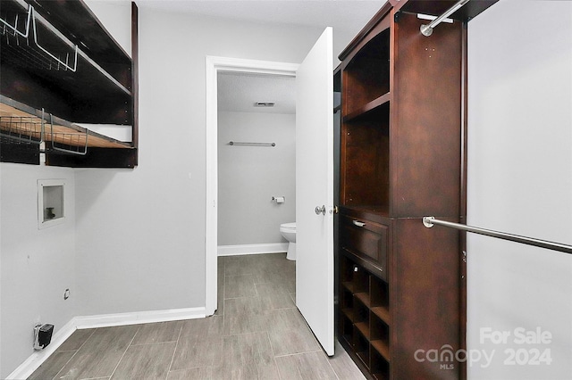 laundry room with hookup for a washing machine, a textured ceiling, and light hardwood / wood-style flooring