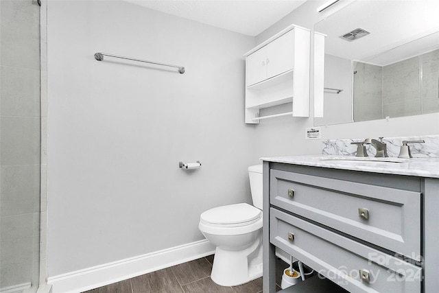 bathroom with hardwood / wood-style floors, walk in shower, toilet, and vanity