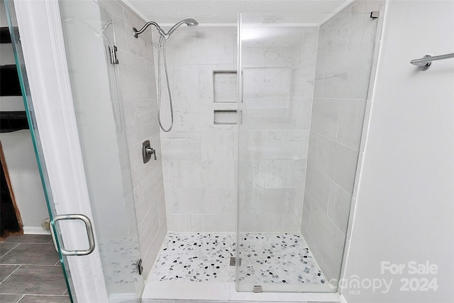 bathroom featuring a textured ceiling and a shower with shower door