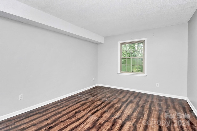 unfurnished room featuring dark wood-type flooring and a textured ceiling