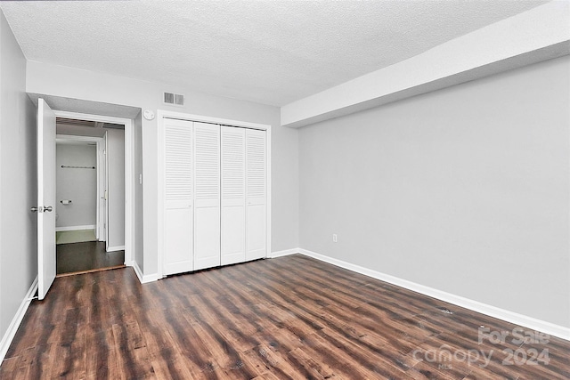 unfurnished bedroom with a closet, dark hardwood / wood-style flooring, and a textured ceiling