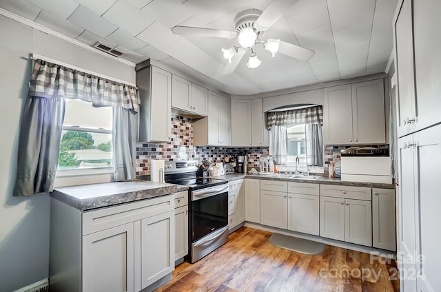 kitchen featuring stainless steel electric range oven, light hardwood / wood-style floors, sink, gray cabinets, and ceiling fan