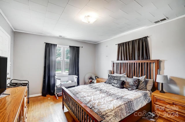 bedroom with light wood-type flooring and ornamental molding