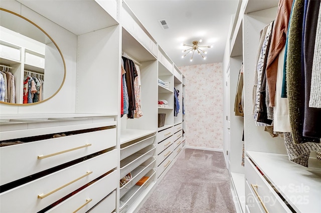 spacious closet with an inviting chandelier and light carpet