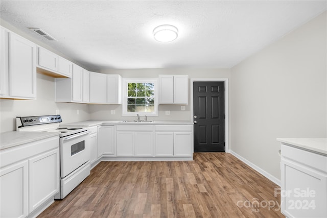 kitchen with a textured ceiling, white range with electric cooktop, sink, white cabinetry, and light wood-type flooring