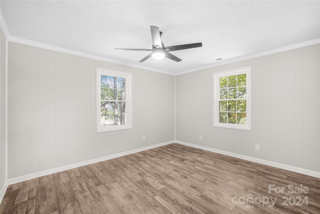 empty room with ceiling fan, plenty of natural light, crown molding, and wood-type flooring