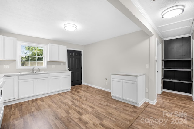 kitchen with light wood-type flooring, white cabinetry, sink, and a textured ceiling