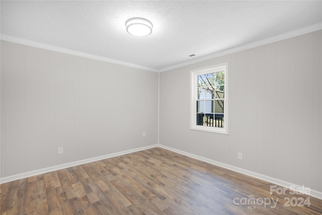 spare room featuring crown molding, a textured ceiling, and wood-type flooring