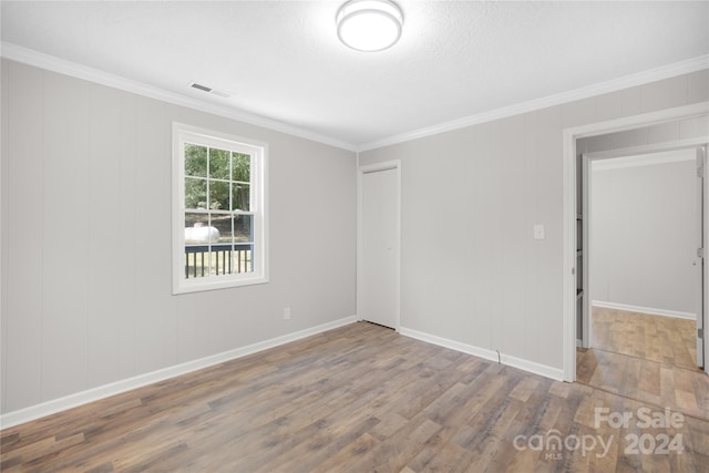 empty room featuring crown molding, a textured ceiling, and wood-type flooring