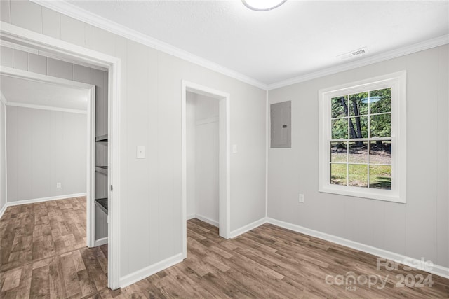 unfurnished bedroom featuring ornamental molding, multiple windows, hardwood / wood-style flooring, and electric panel