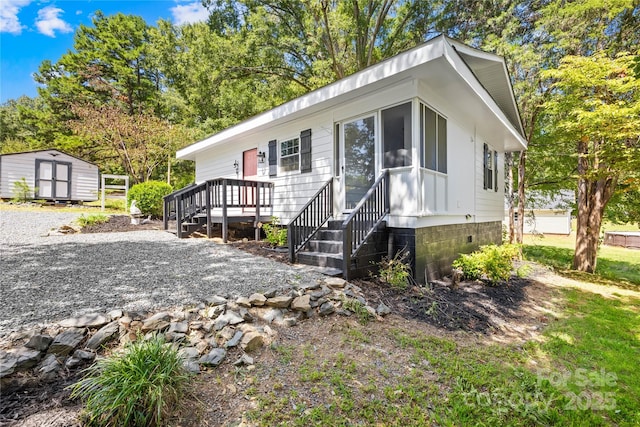 view of front of property with a storage shed, crawl space, an outdoor structure, and gravel driveway