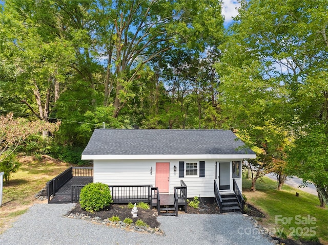 single story home featuring a shingled roof and a wooden deck