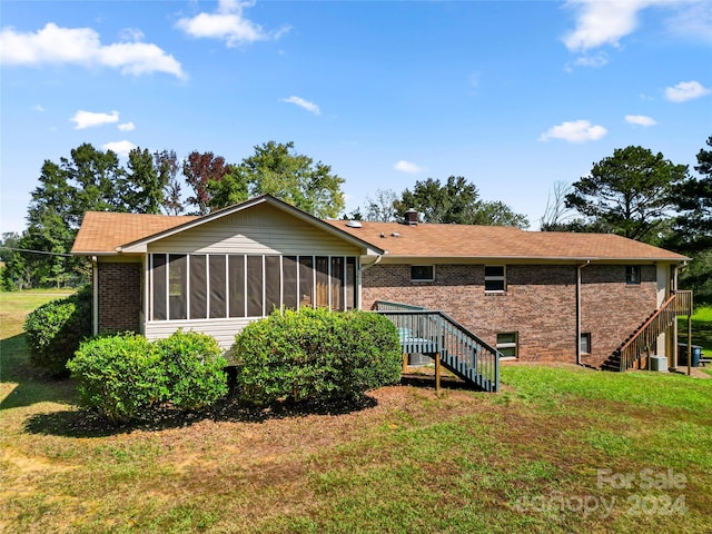 rear view of property with central air condition unit, a lawn, and a sunroom