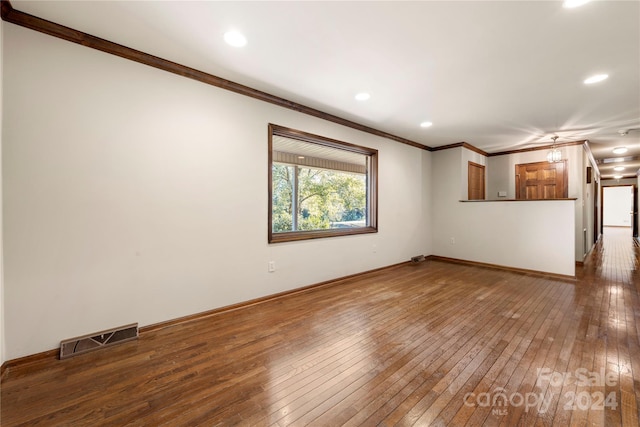 unfurnished living room featuring dark hardwood / wood-style flooring and crown molding