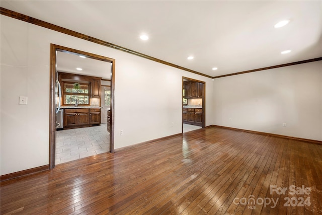 spare room with light wood-type flooring and ornamental molding