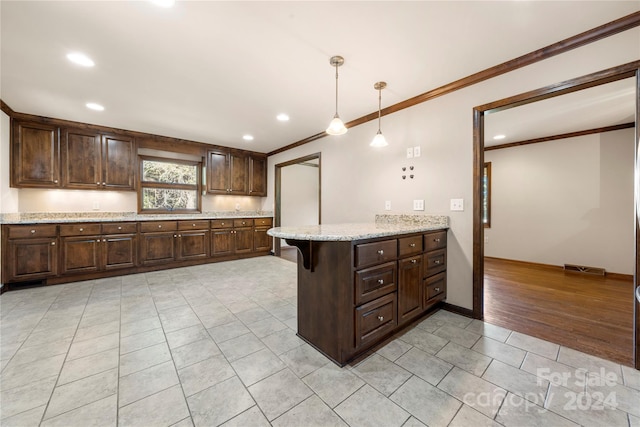 kitchen with a kitchen bar, hanging light fixtures, light wood-type flooring, light stone counters, and kitchen peninsula