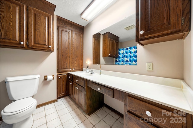 bathroom featuring toilet, a textured ceiling, vanity, and tile patterned floors