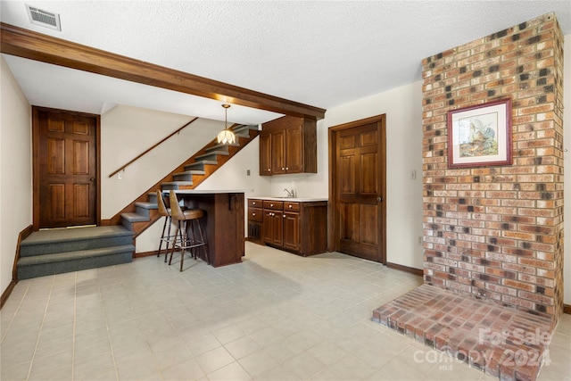 kitchen with sink, decorative light fixtures, a kitchen breakfast bar, and a textured ceiling