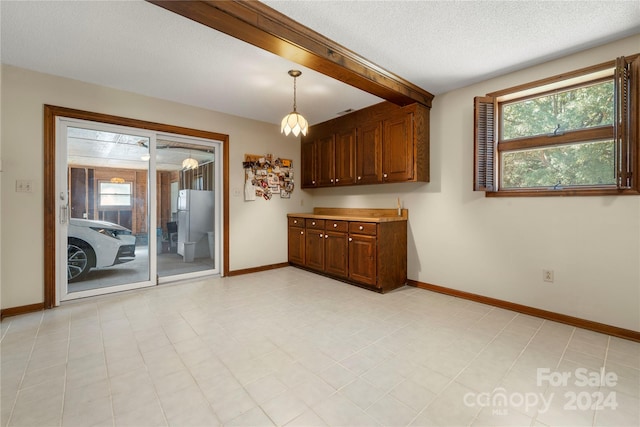 interior space featuring beamed ceiling, plenty of natural light, and a textured ceiling