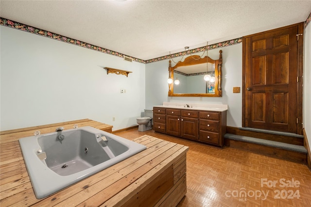 bathroom featuring vanity, parquet floors, toilet, a textured ceiling, and a tub