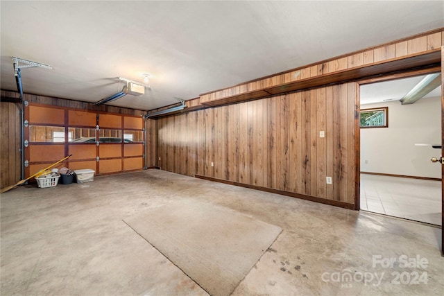 garage featuring a garage door opener and wooden walls