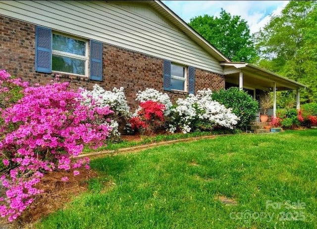 view of side of home featuring brick siding and a lawn